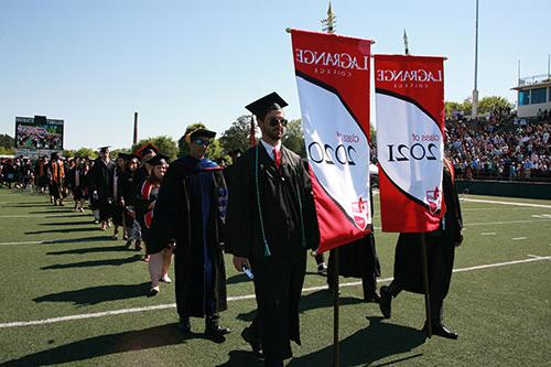 Commencement march - two men carry banners to lead both classes in